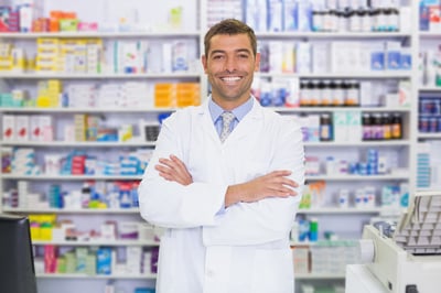 Handsome pharmacist smiling at camera at the hospital pharmacy