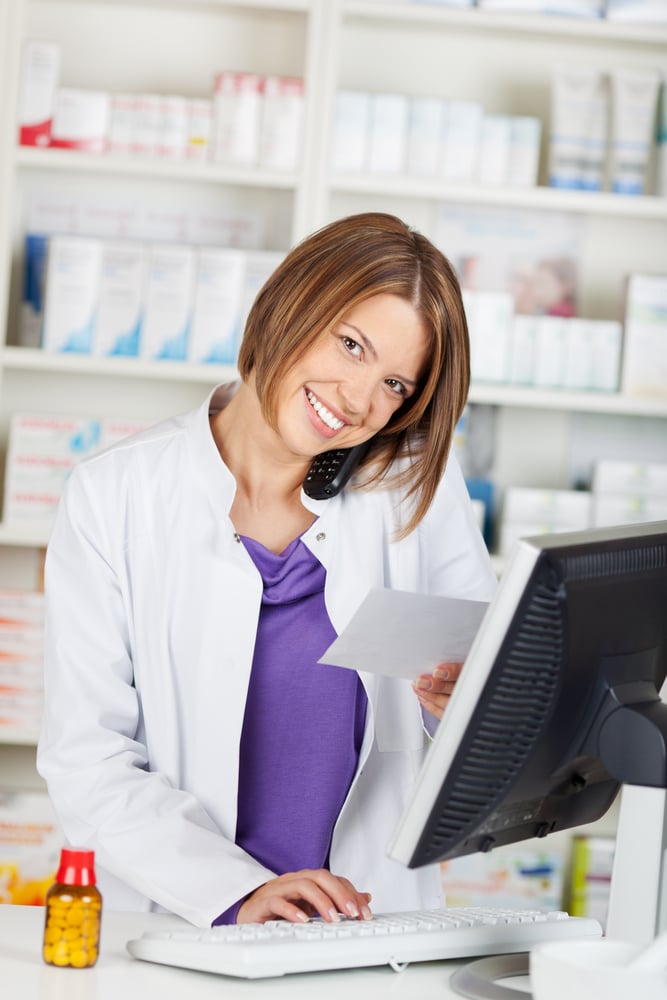Portrait of calling female pharmacist in front of shelves